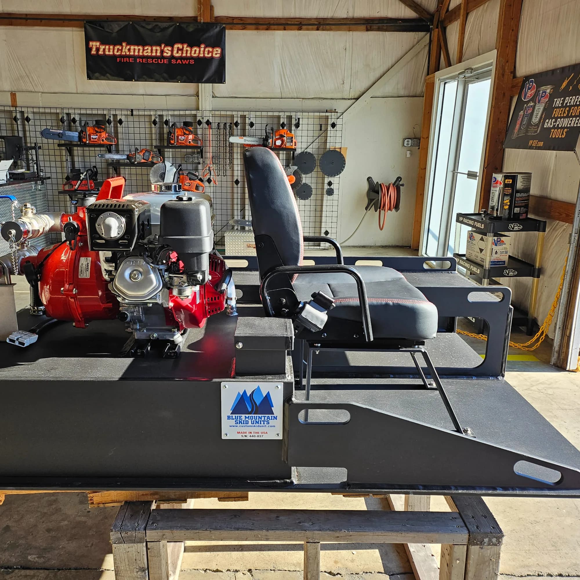 Blue Mountain Skid Units nameplate and serial number on an EFES-built UTV skid, with a red gas-engine fire pump at one end and a padded attendant seat with a grab rail on the deck
