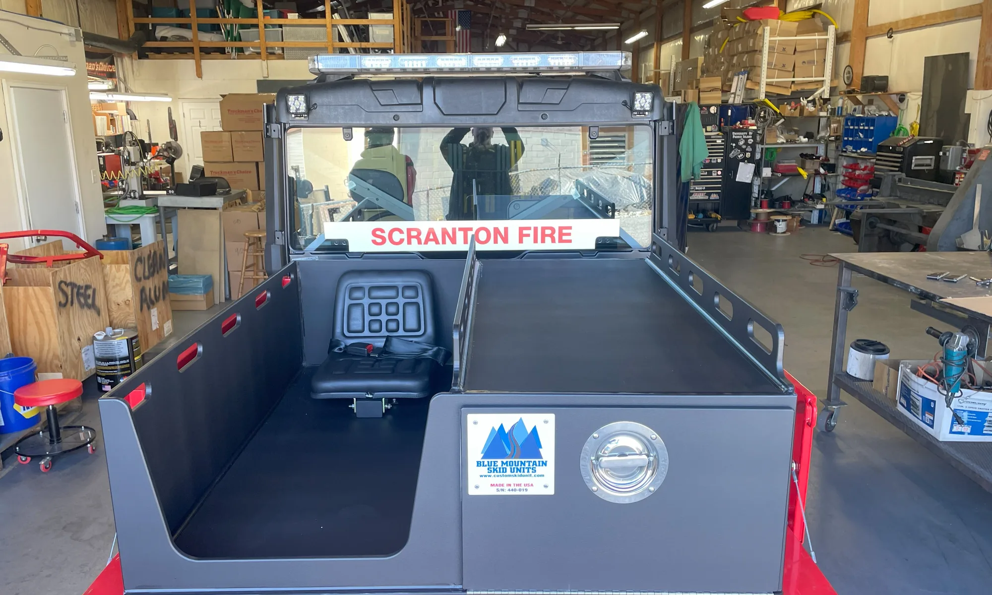 Rear view of a medical skid in a UTV showing the belted attendant seat, the flat railed litter deck, and the enclosed storage compartment underneath