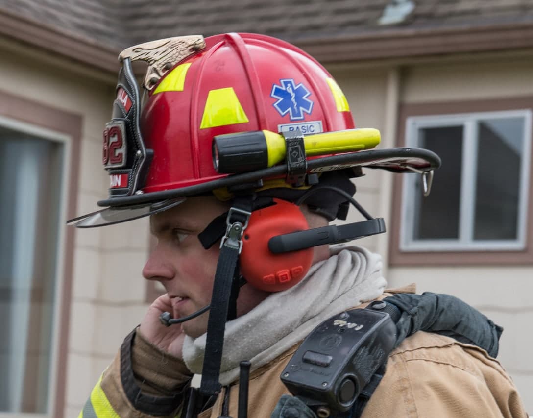 Firefighter wearing a FIRECOM under-helmet wired headset with the boom microphone in position