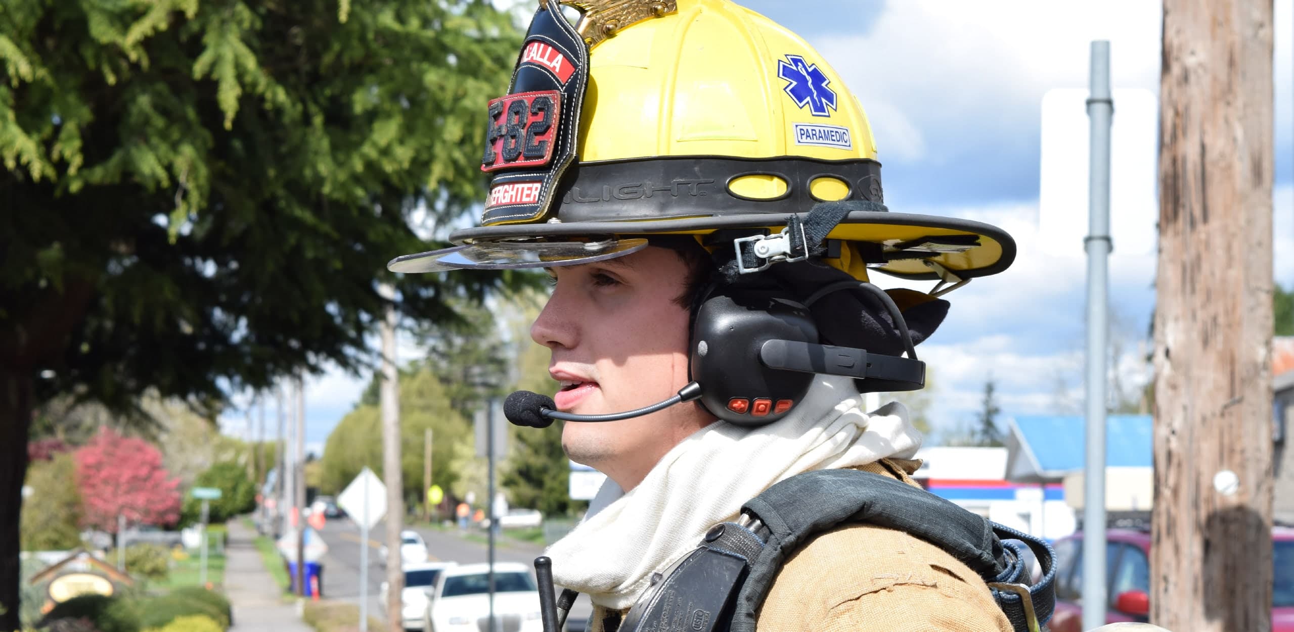 Firefighter using a FIRECOM headset beside a fire apparatus