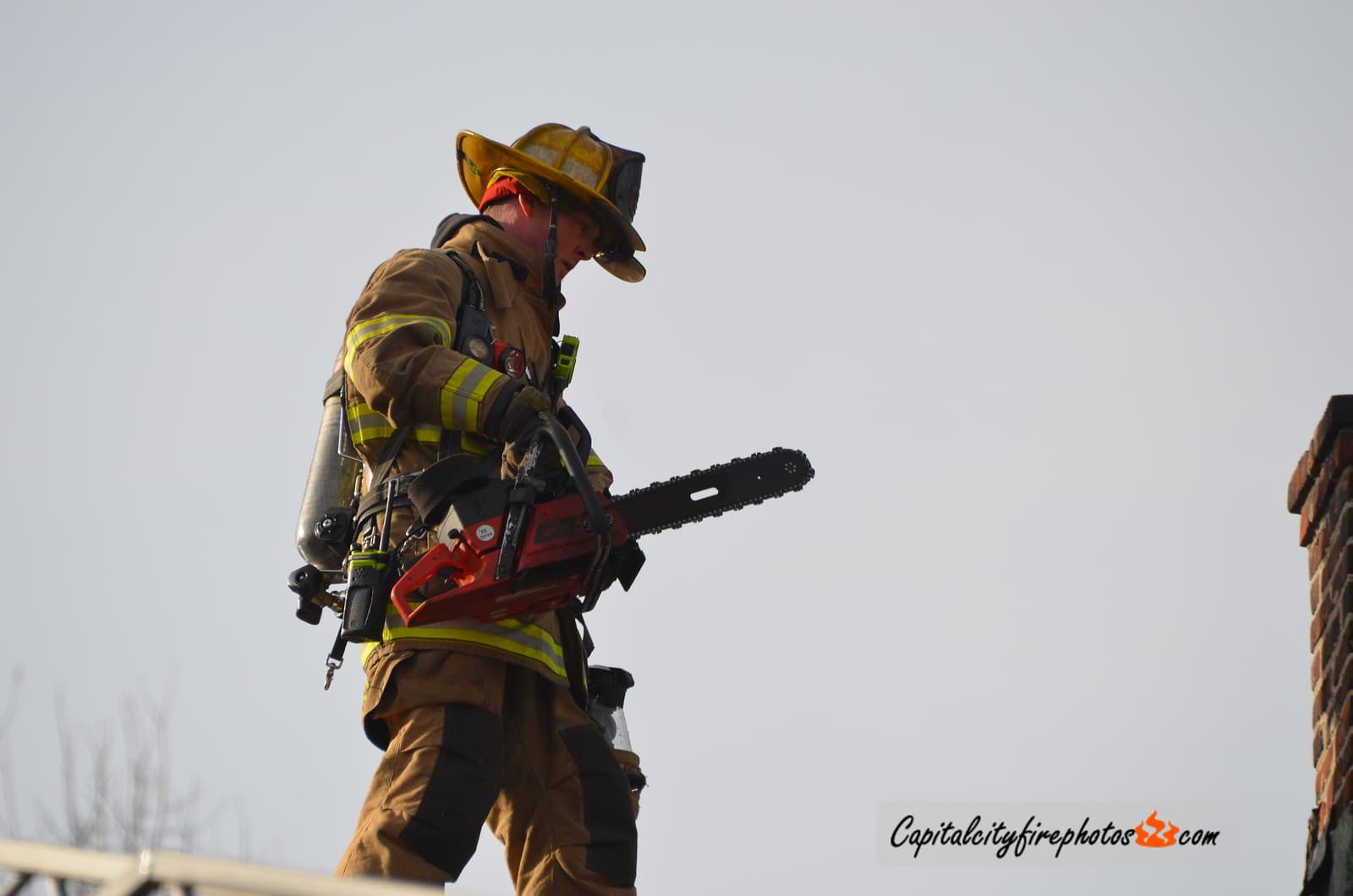A firefighter carrying a rescue saw during roof operations